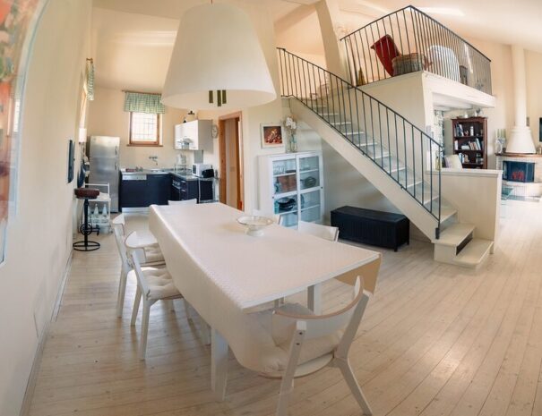 Vista open space del Loft Verdemare a Fano con cucina attrezzata, zona pranzo, soggiorno con camino e soppalco – ideale per vacanze in famiglia nelle Marche.