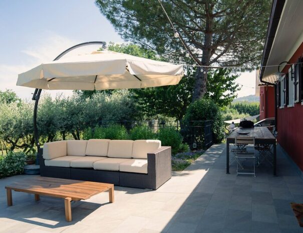 Spazioso patio del Loft Verdemare a Fano con divano da esterno, ombrellone, tavolo da pranzo e vista sul verde – perfetto per vacanze nelle Marche.