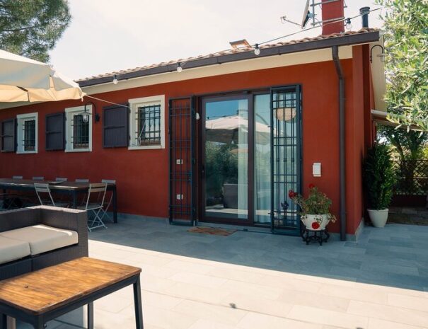 Loft Verdemare a Fano con ingresso indipendente, patio arredato e area relax all’aperto – affitto turistico ideale vicino al mare. Casa vacanze moderna con pareti rosso scuro, infissi bianchi, porta scorrevole in vetro, grate di sicurezza e arredamento da giardino. Alloggio perfetto per soggiorni a Fano, nelle Marche, in zona tranquilla e verde.